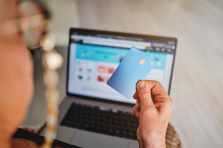 Adult woman holding a card with her hand in front of the computer about to pay see how to accept payments online for a purchase